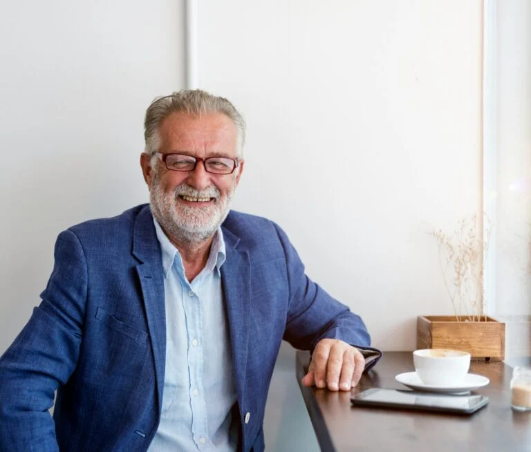 Smiling man in his 50s seated at a café table