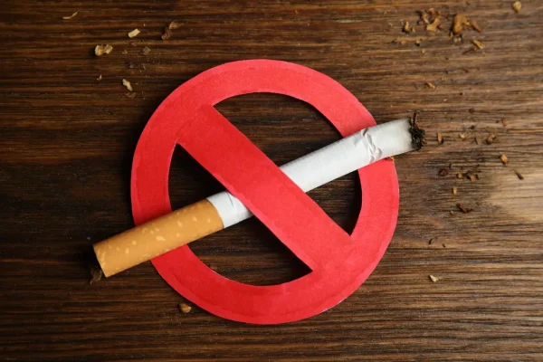 Cigarette with prohibition sign on wooden table, top view. Quitting smoking concept