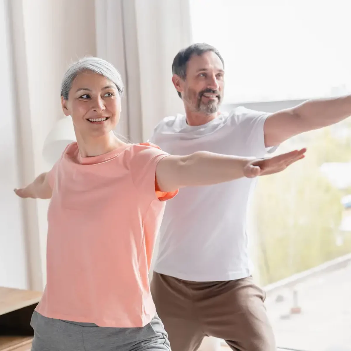 Fit sporty mature couple family spouses training stretching doing yoga exercises at home on lockdown. Middle-aged wife and husband doing sport together